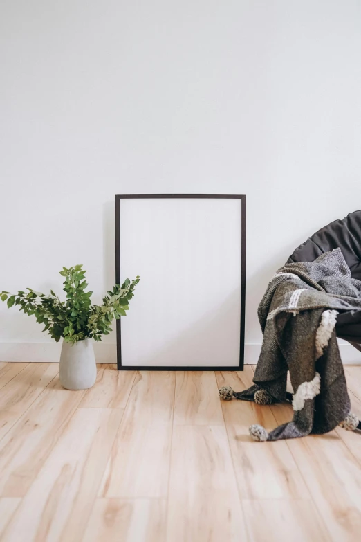 a couch, chair and empty framed picture on a wooden floor