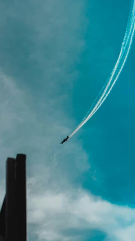 a jet plane flying through the sky behind a smoke stack