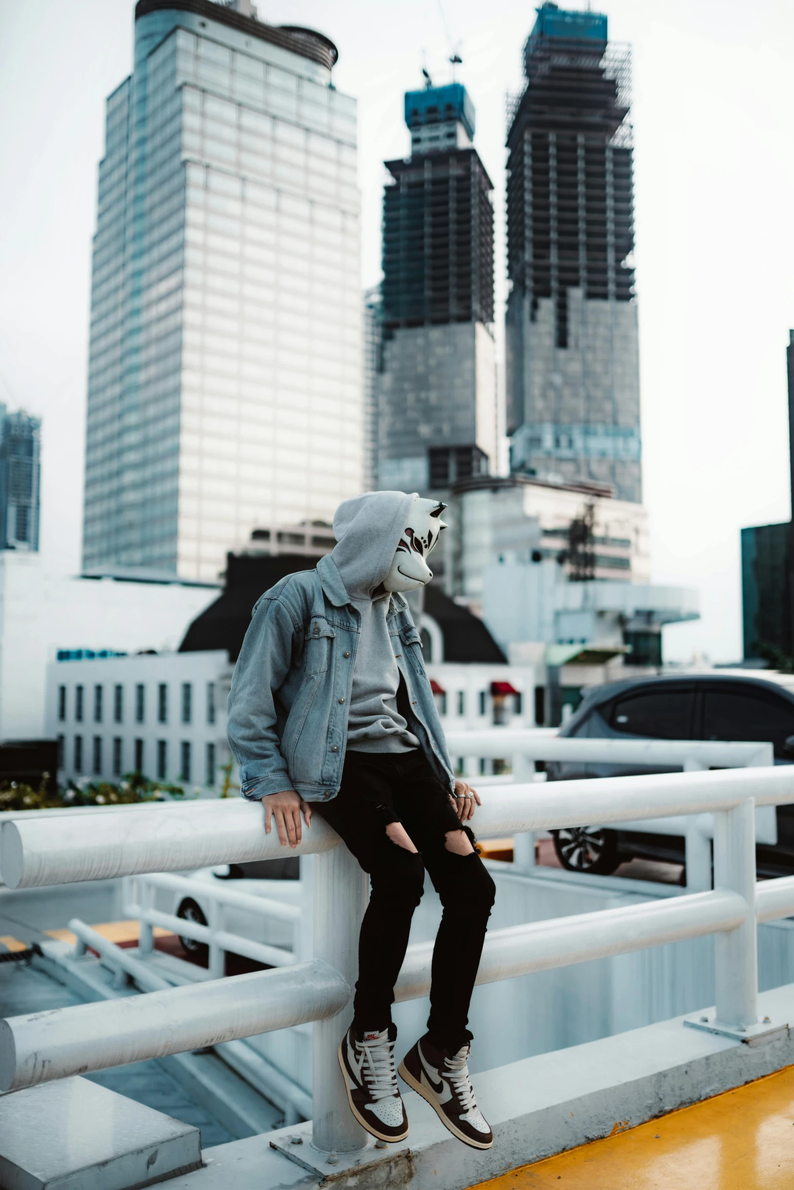 a man standing on top of a white fence near a highway