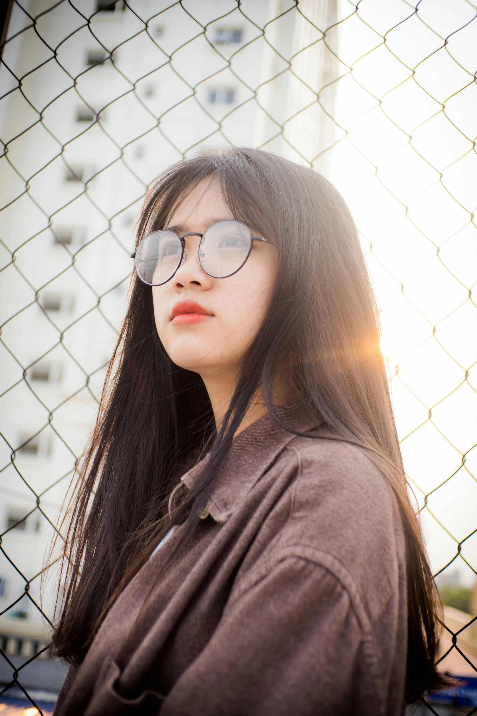 a woman is wearing glasses and standing near a fence