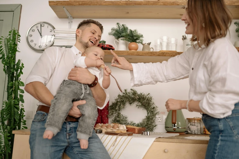 a man and a woman hold their small child in their kitchen