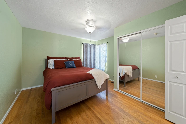 a bed sitting in the corner of a room under a mirror