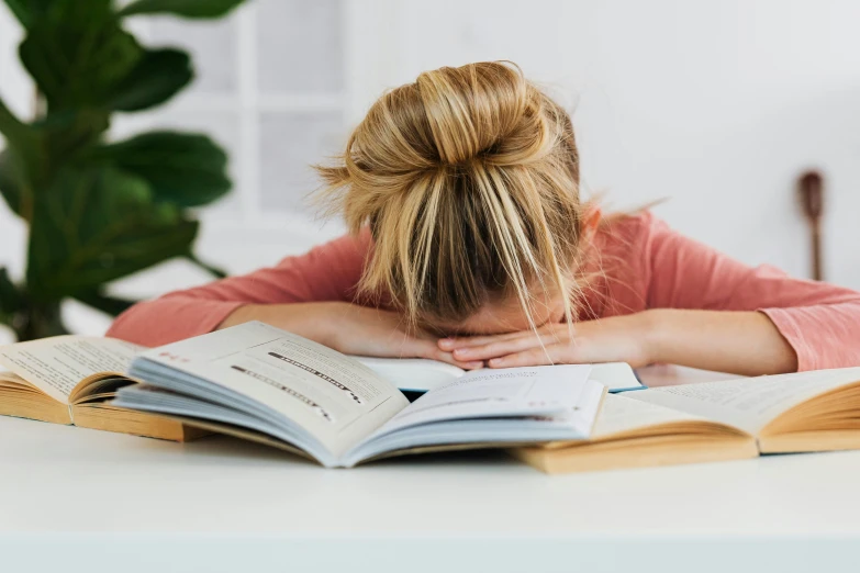 a woman is leaning her head on her book and looking at them