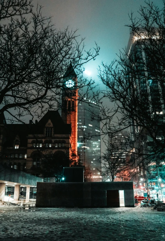 a clock tower near many buildings at night