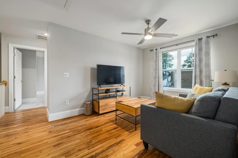 the living room has wooden floors and a ceiling fan