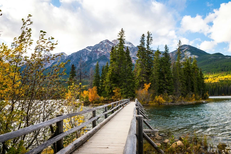 a small bridge on the side of a river leading to mountains