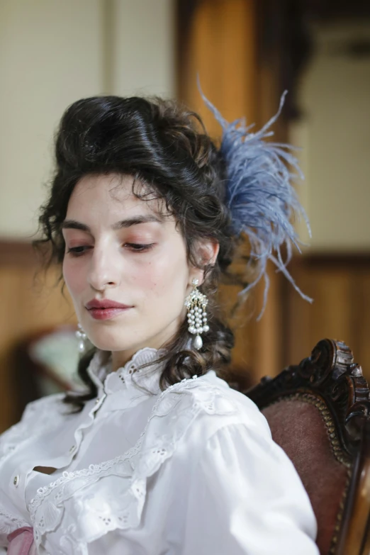 woman in white blouse with blue feathers on her head