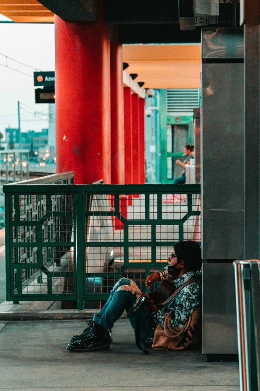 a woman sitting on a bench under a green pole