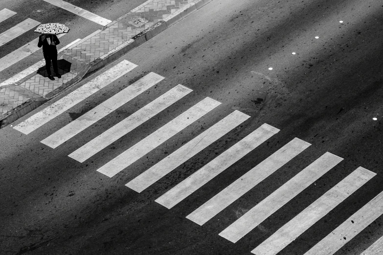 the people are walking across the crosswalk carrying an umbrella