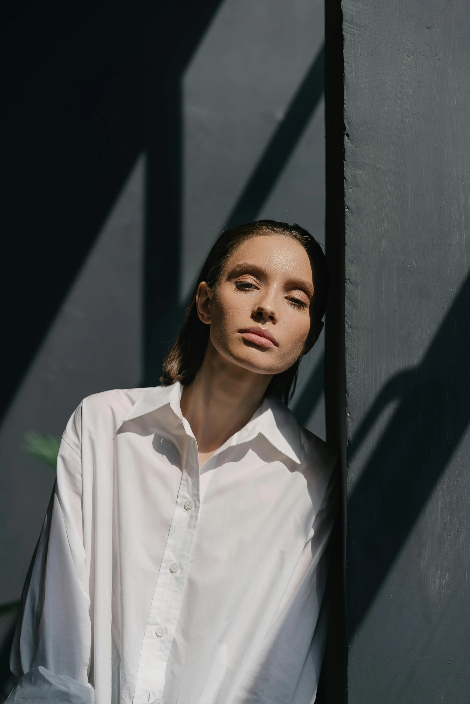 a woman leans against the wall with her head hanging on her shoulder