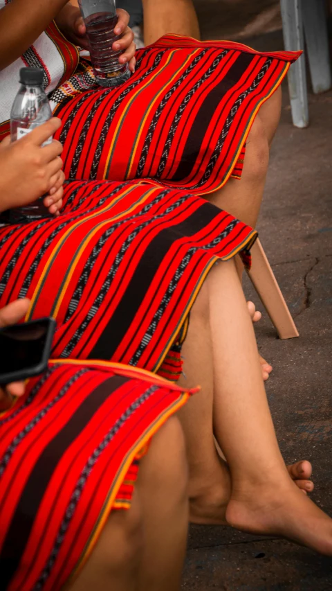 three women sitting on top of a brown bench