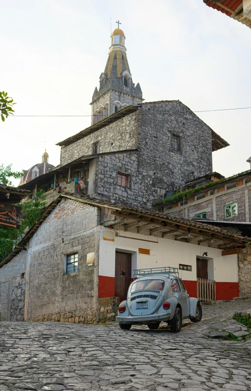 small car parked on a cobblestone driveway in front of old buildings