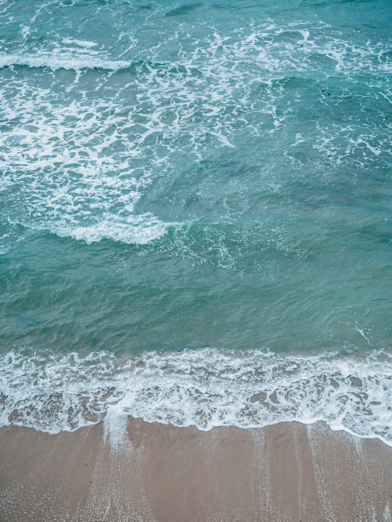 waves crashing on the beach with clear blue water