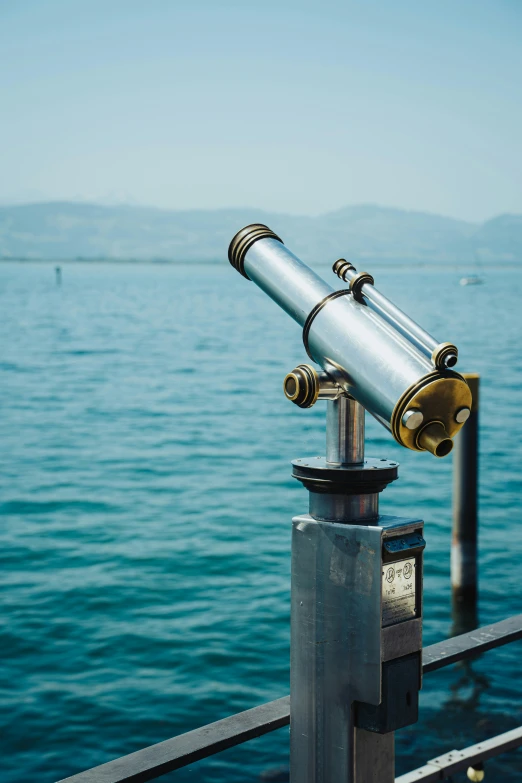 a telescope on top of a metal post overlooking the ocean