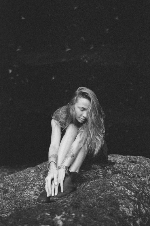 a woman laying on top of a large rock