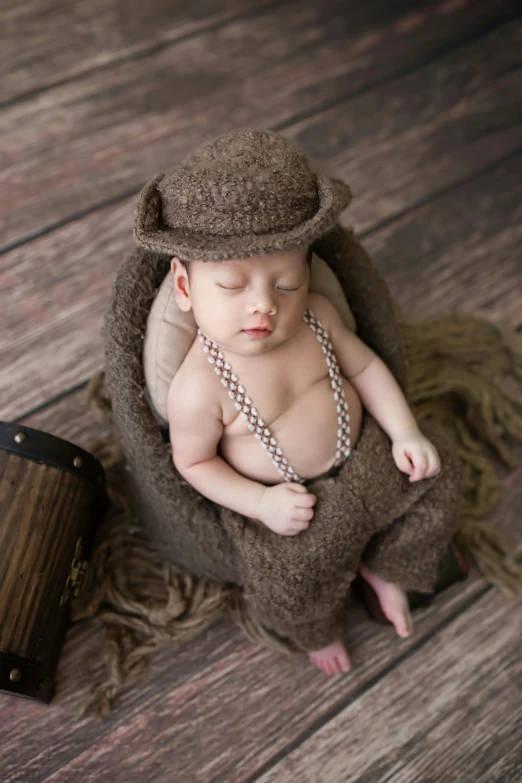 a baby wearing a hat and beads is curled up