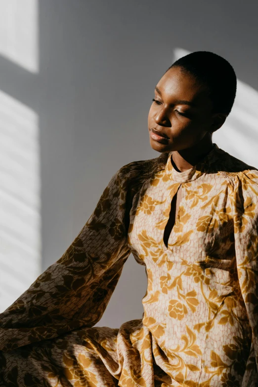 a woman in a yellow dress sits with her arms crossed