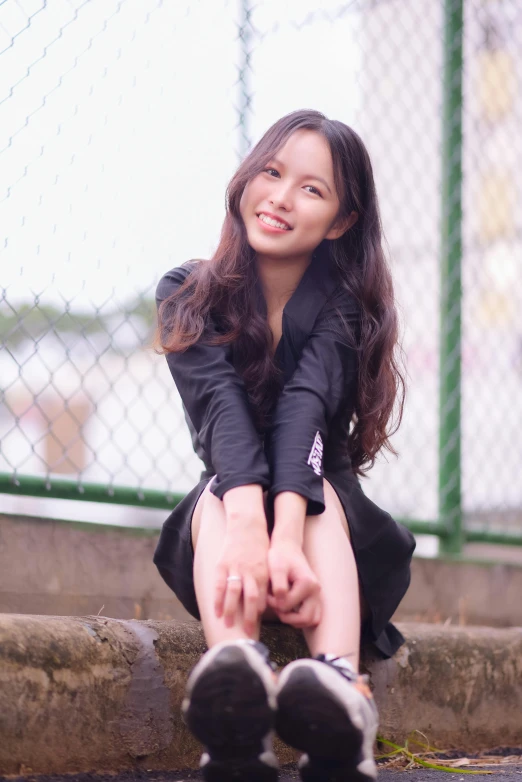 a young woman in a black dress holding her leg up on the ground