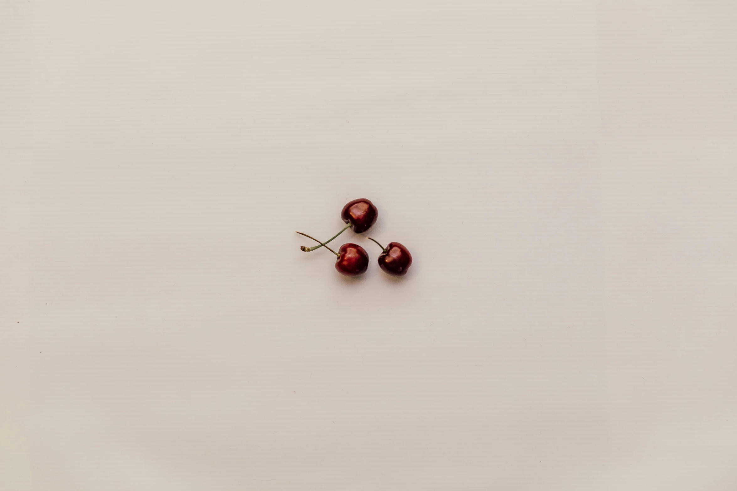 three berries lie on a plain surface in this still image