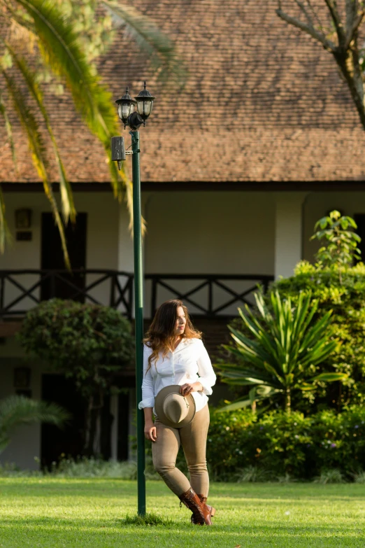 a woman leaning on a light pole in the middle of a lawn