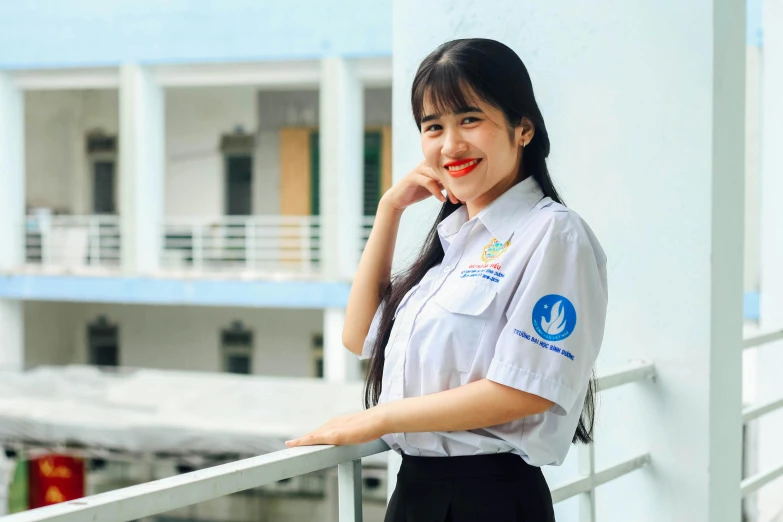 an asian girl wearing a uniform stands on the balcony