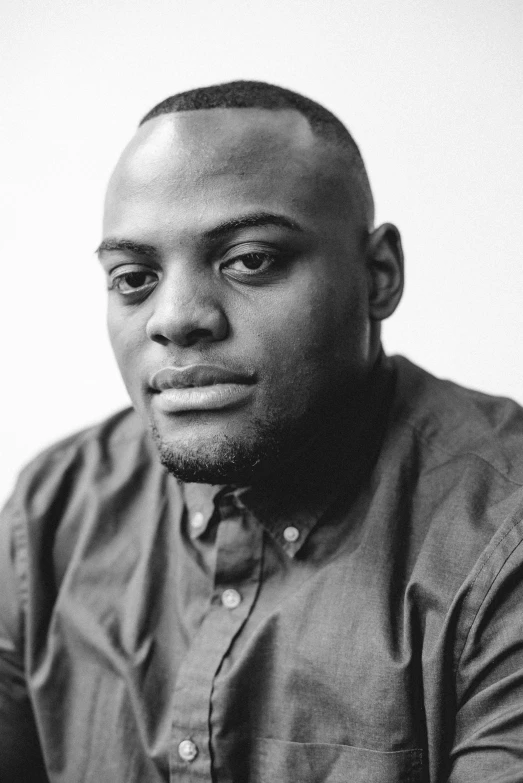 a man poses in front of a white wall