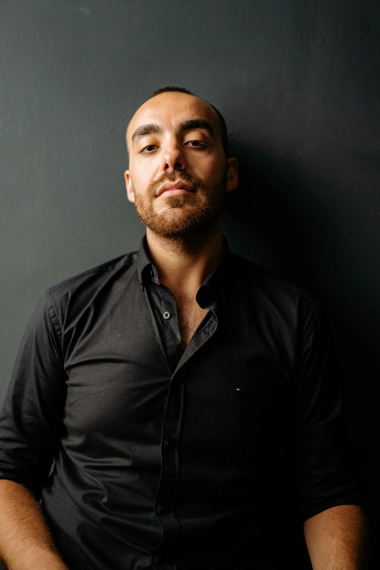 a man in a black shirt posing for a portrait