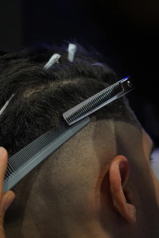 a person sitting down  their hair with a pair of scissors