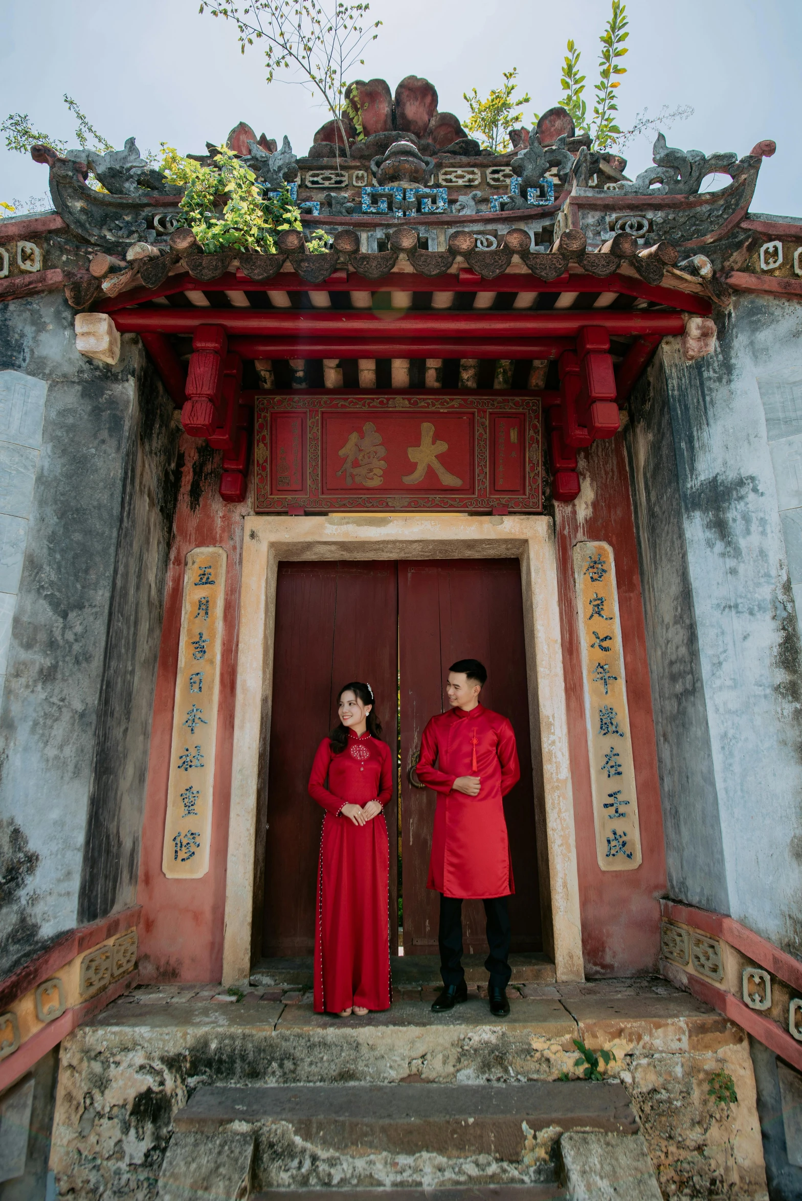 two people in long red dresses standing at the entrance to an ancient temple