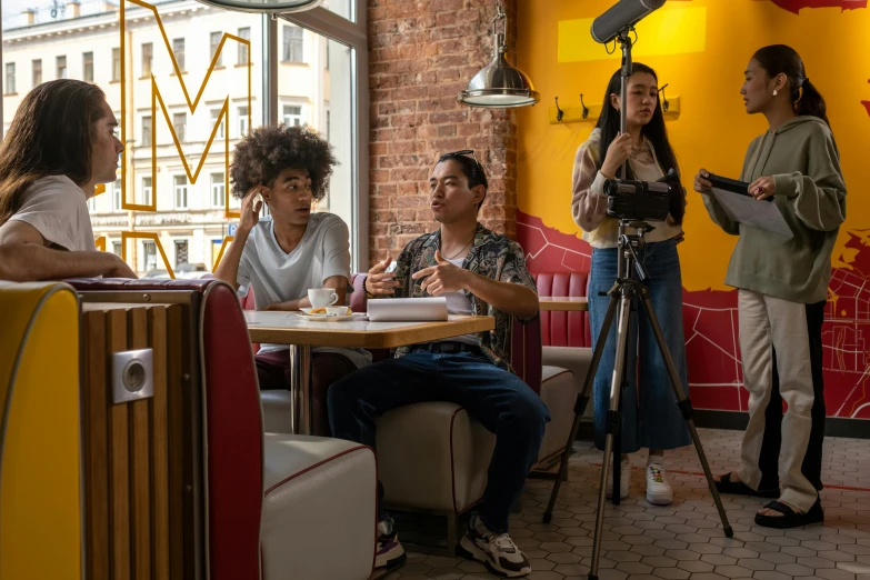 three people are sitting at a table having conversation