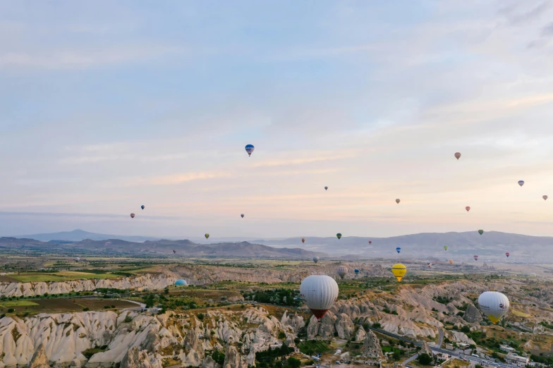 several balloons fly above rocky terrain and mountains