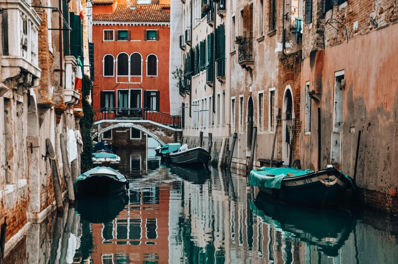 many boats sit on the water in a narrow canal