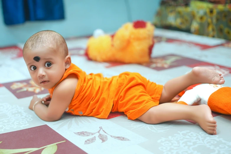 a young child lies on the floor next to a stuffed animal