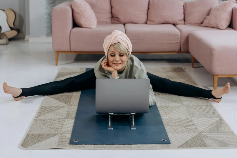 a woman on a yoga mat with her laptop in her lap