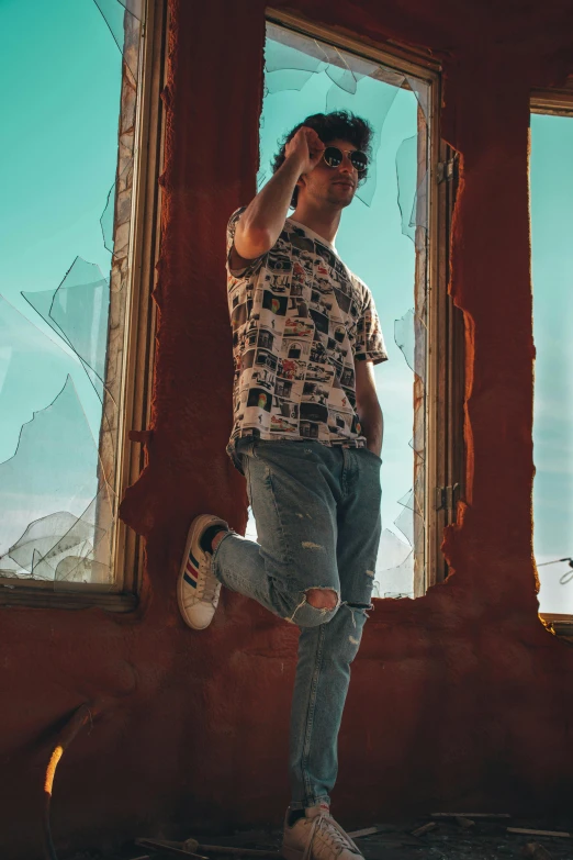 man standing in front of a broken window wearing ripped jeans