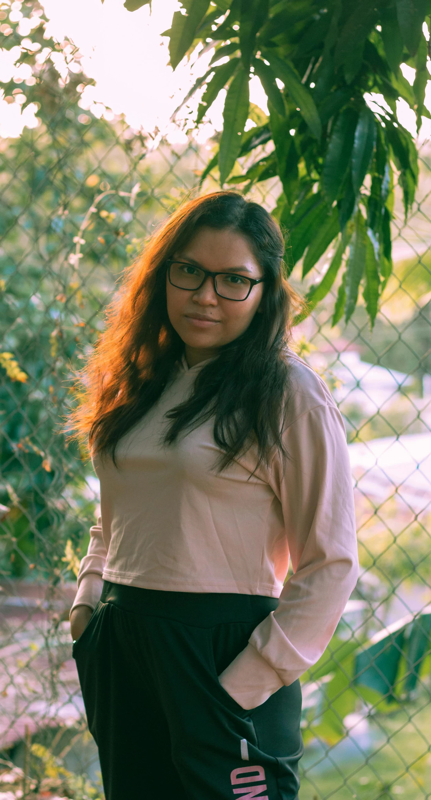 the woman is standing against the chain link fence