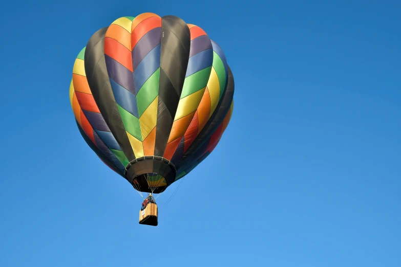 a multi - colored  air balloon flying in the sky
