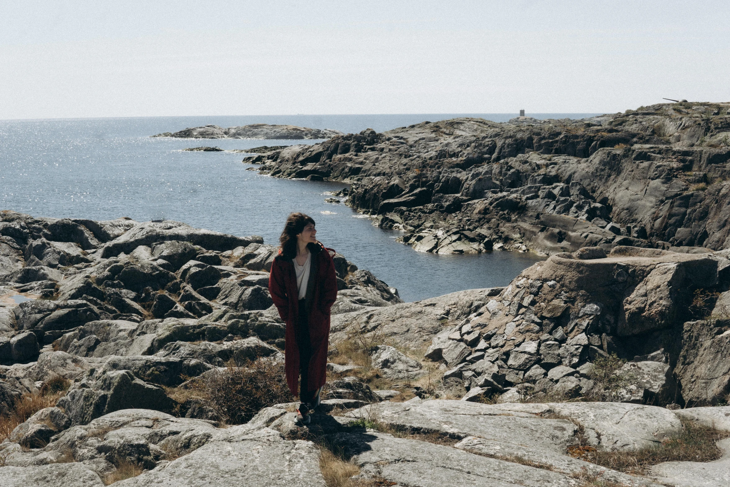 a woman is standing on the rocks overlooking a body of water