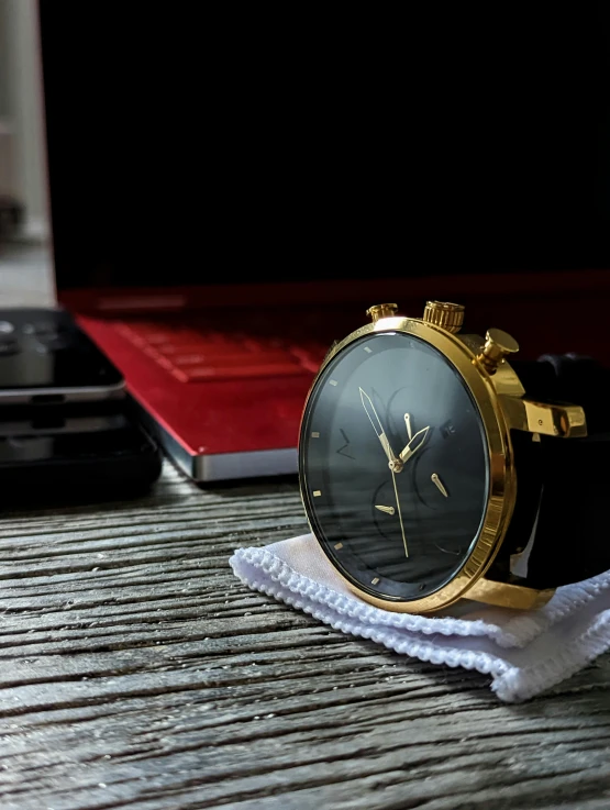 an antique style watch on a table next to a red notebook