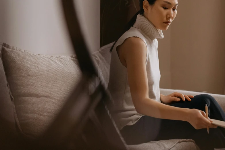 a woman sitting on a white couch with a white pillow