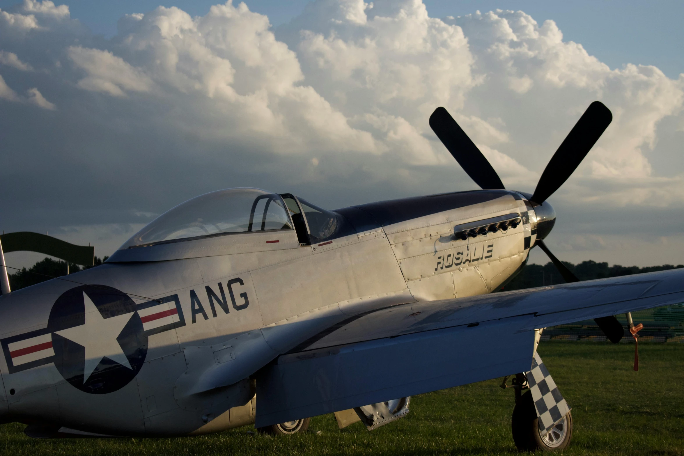 a silver old plane sitting on top of a field