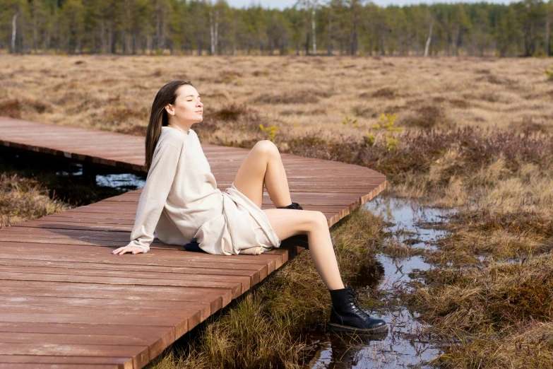 a woman sitting on a dock at the edge of a swamp