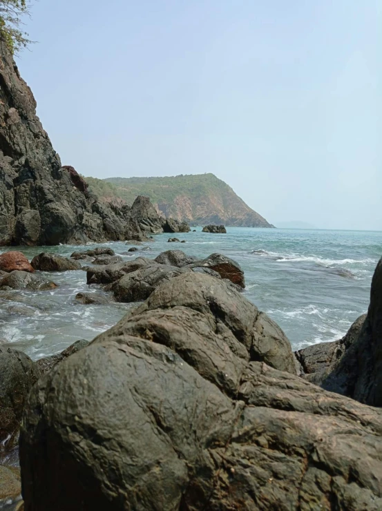 there is rock next to the ocean with a bench on it