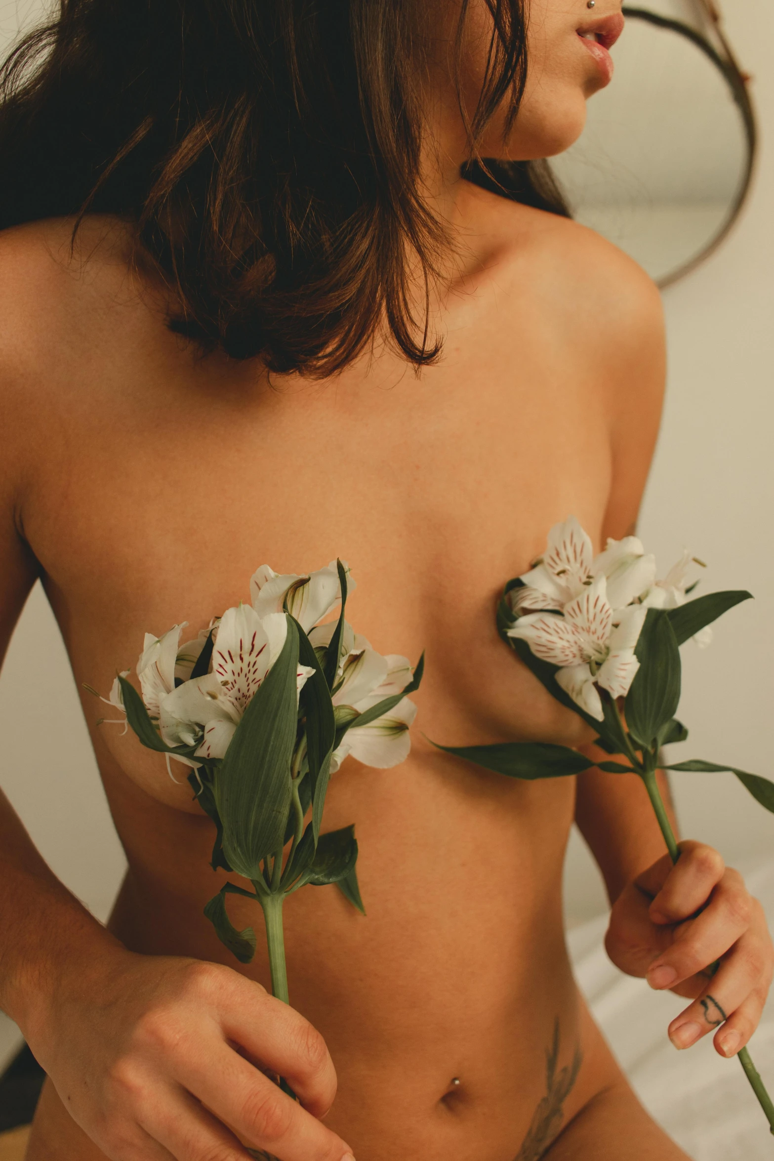 a woman with bare bottom holding flowers and looking off to the side