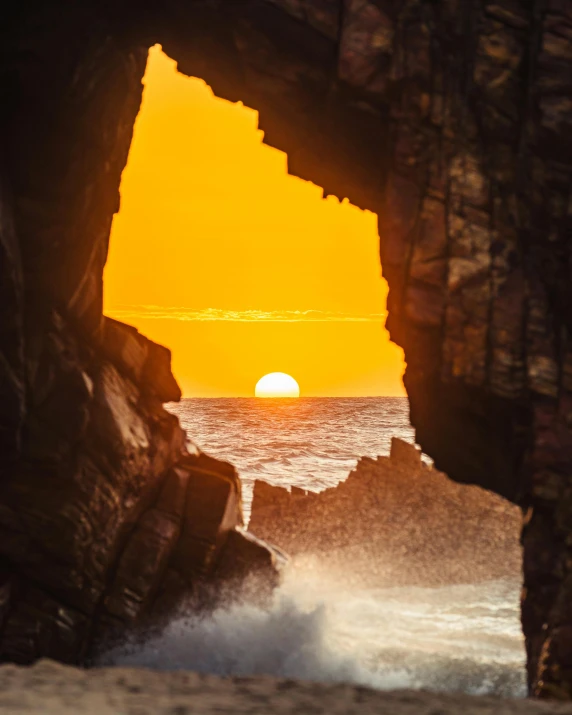 sunset view through opening in rock on ocean