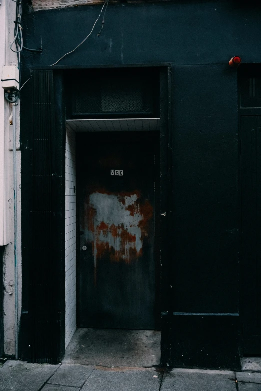 the doorway to an alley building is painted black