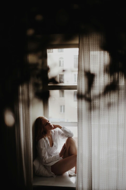 a woman is sitting on the window sill