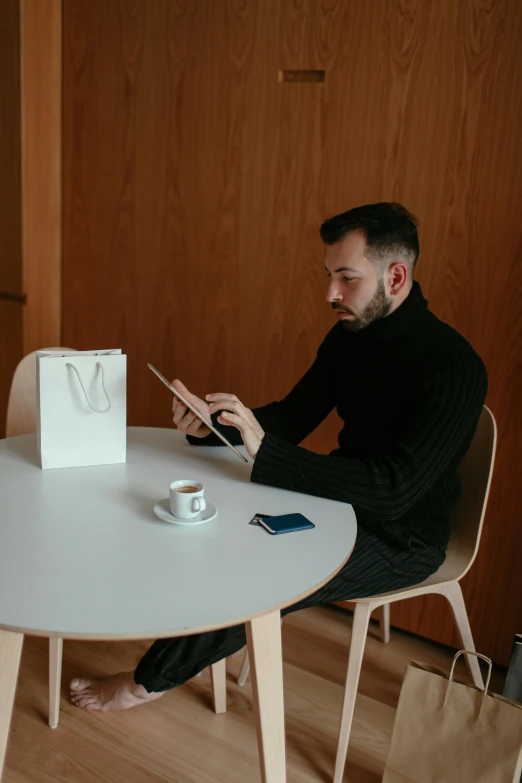 man with cup, paper bag and stick sitting at table