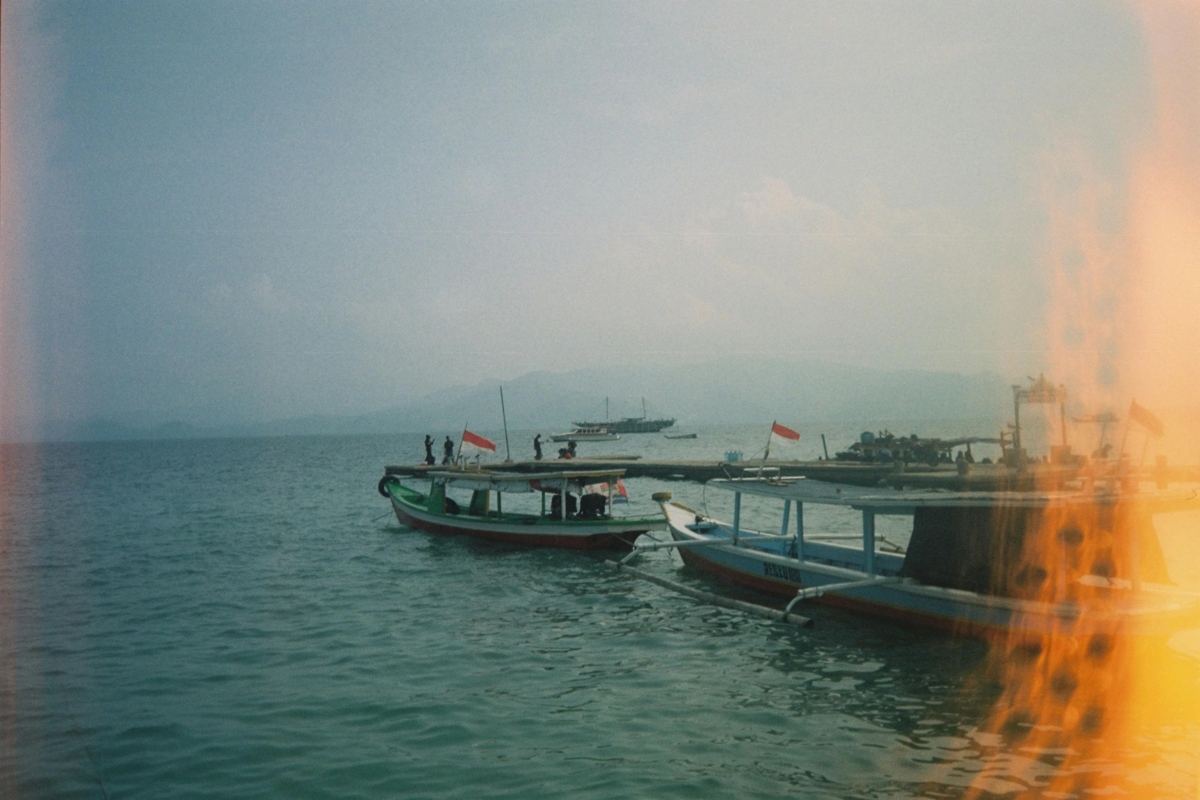 two boats with people in the front of them traveling on a body of water