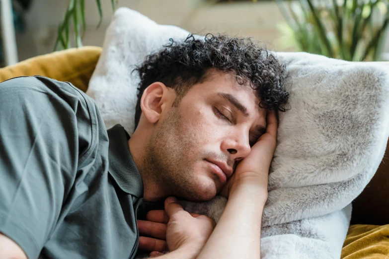 man sleeping on a sofa with a fluffy pillow